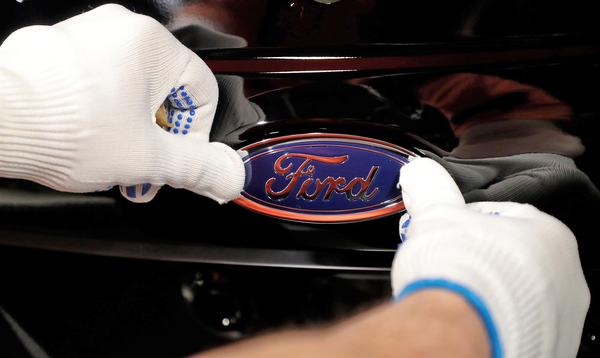 Fotografía de archivo que muestra a un empleado del fabricante de automóviles Ford mientras coloca el logotipo de la empresa en un vehículo. EFE/ Friedemann Vogel
