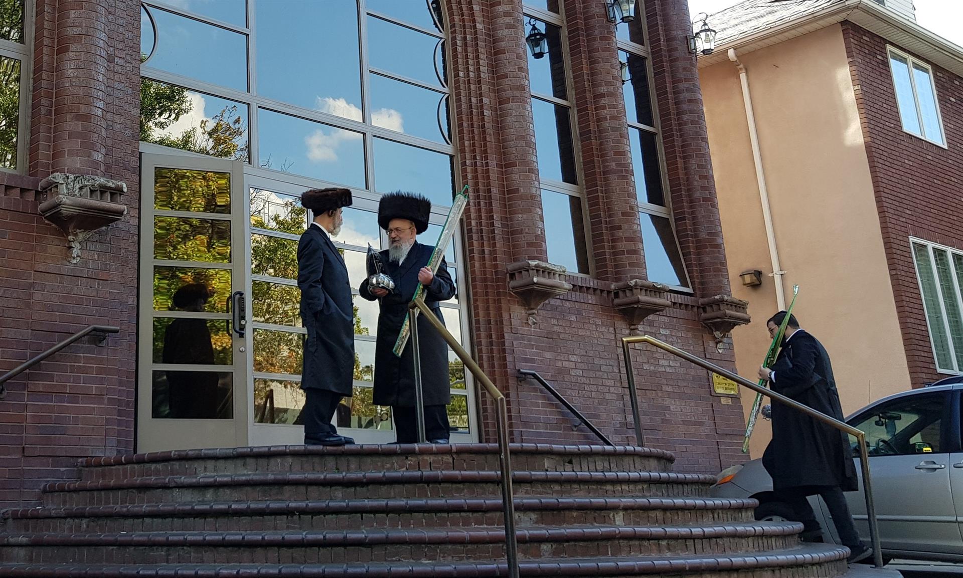 Unos judíos ultraortodoxos conversan sin llevar mascarilla en la puerta del centro religioso Yeshiva Beth Yitzchok D'spinka en Nueva York. EFE/Jorge Fuentelsaz
