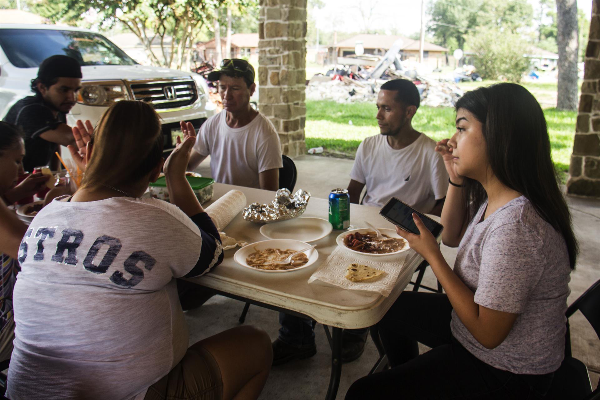 Fotografía de archivo del 24 de septiembre de 2017 que muestra a un grupo de hispanos mientras almuerzan en el portal de una vivienda de Houston, Texas, que sufrió daños por las inundaciones durante el paso de Harvey. EFE/Alicia L. Pérez

