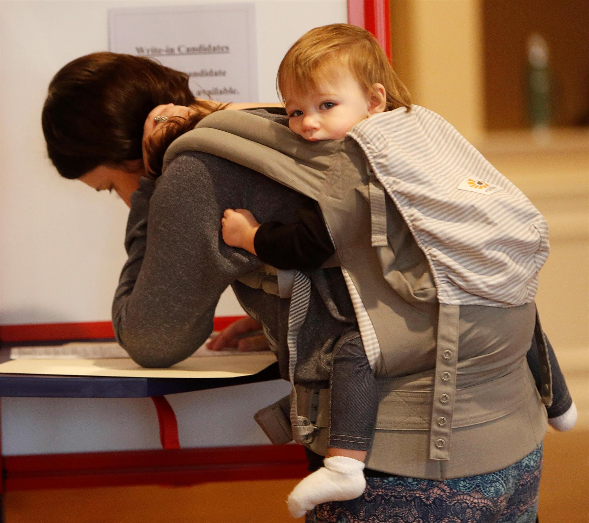 Fotografía de archivo de una mujer que carga a su niño mientras llena unas formas, en EEUU. EFE/DAVID MAXWELL

