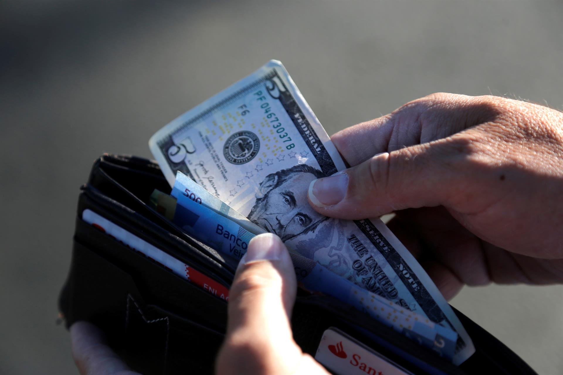 Una persona guarda en su cartera un billete de cinco dólares en Tepatitlán, estado de Jalisco (México). EFE/ Francisco Guasco
