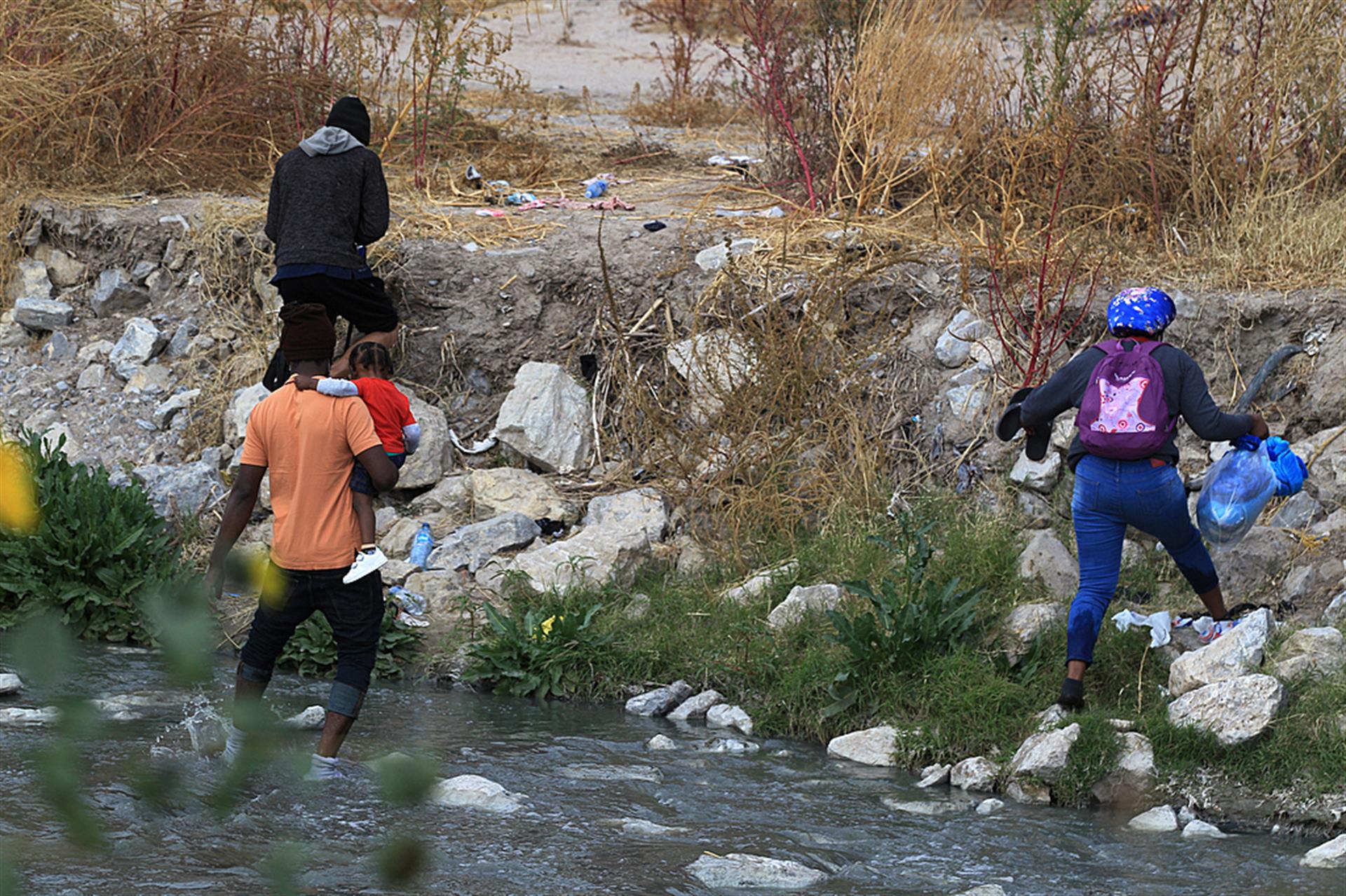 Una familia de migrantes haitianos cruzan las aguas del Río Bravo a la altura del puente Internacional Paso del Norte el 27 de diciembre de 2021 en Ciudad Juárez, estado de Chihuahua (México). EFE/Luis Torres.
