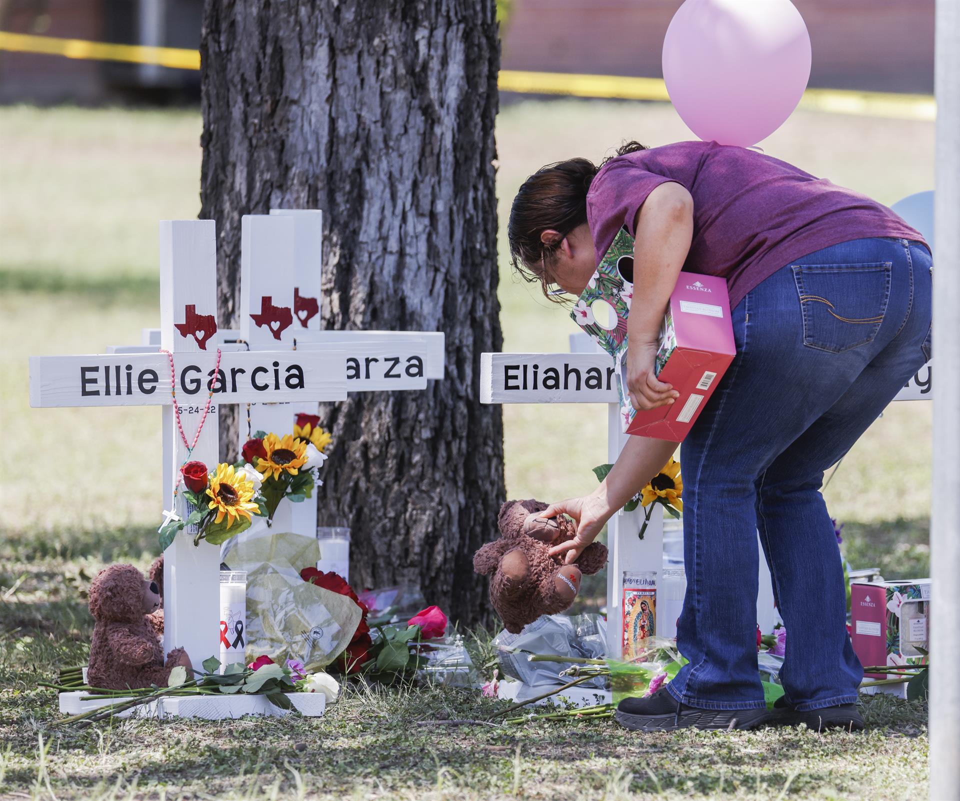 Uvalde (United States), 26/05/2022.- A woman places a stuffed animal by a cross bearing a victim's name following a mass shooting at the Robb Elementary School in Uvalde, Texas, USA, 26 May 2022. According to Texas officials, at least 19 children and two adults were killed in the shooting on 24 May. The eighteen-year-old gunman was killed by responding officers. (Estados Unidos) EFE/EPA/TANNEN MAURY
