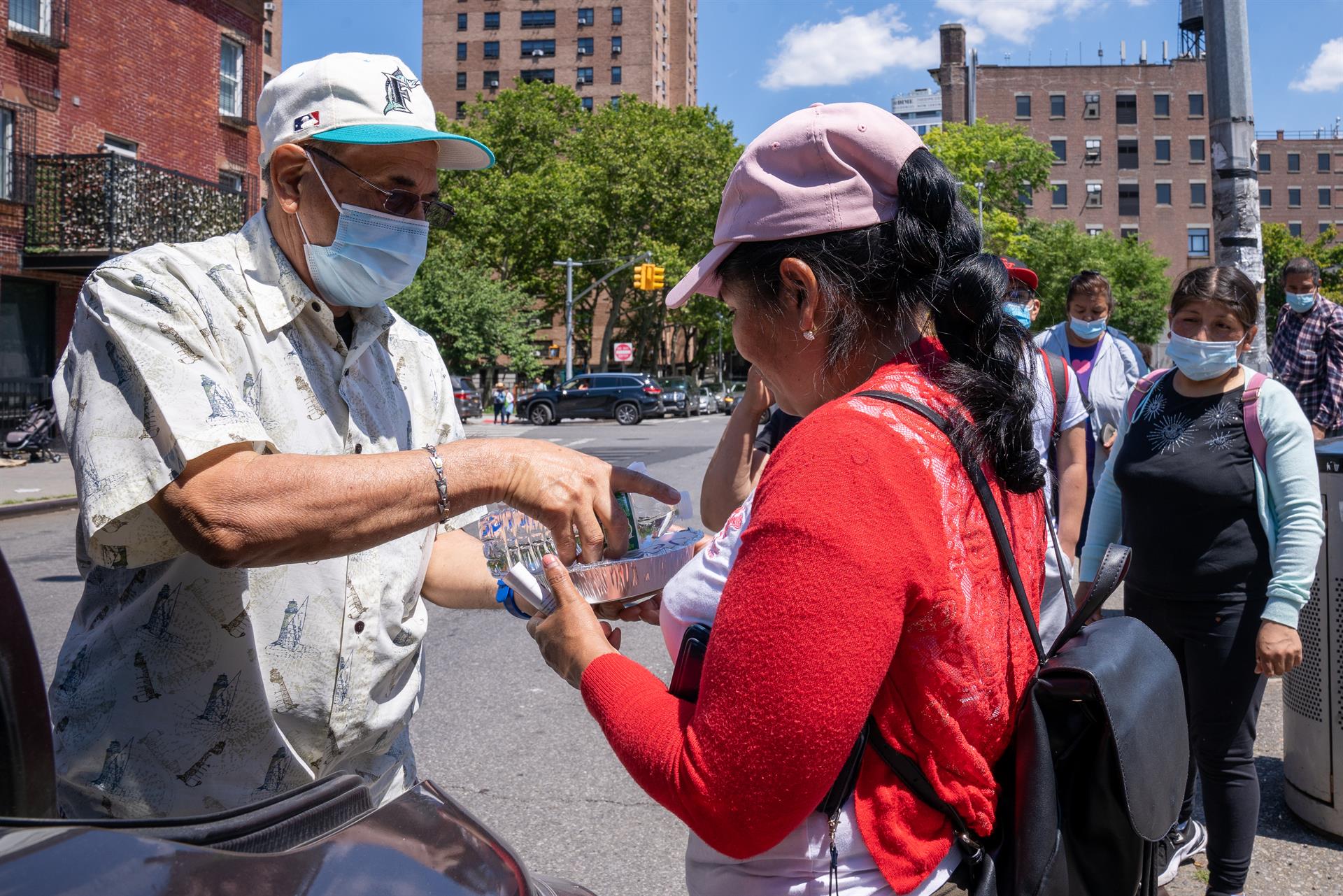Un grupo de mujeres jornaleras inmigrantes reciben comida mientras esperan ser contratadas para trabajos de limpiezas, el 29 de junio de 2022 en la plaza de un vecindario judío hasídico de Brooklyn en Nueva York (EE. UU). EFE/Ángel Colmenares

