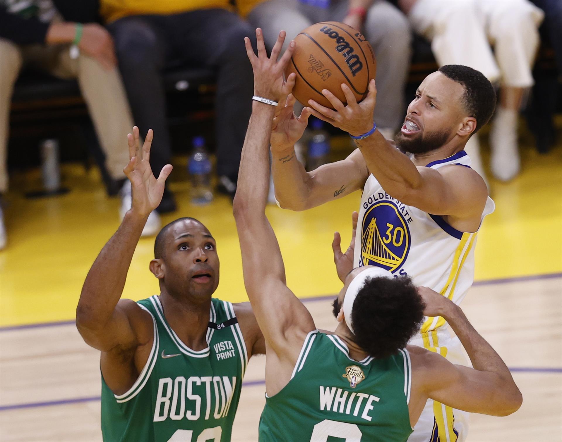 El escolta de los Golden State Warriors, Stephen Curry (d) remata por encima de los jugadores de los Boston Celtics, Al Horford (i) y Derrick White (C) durante el segundo cuarto del segundo partido. de la serie final de la Asociación Nacional de Baloncesto (NBA). EFE JOHN G. MABANGLO
