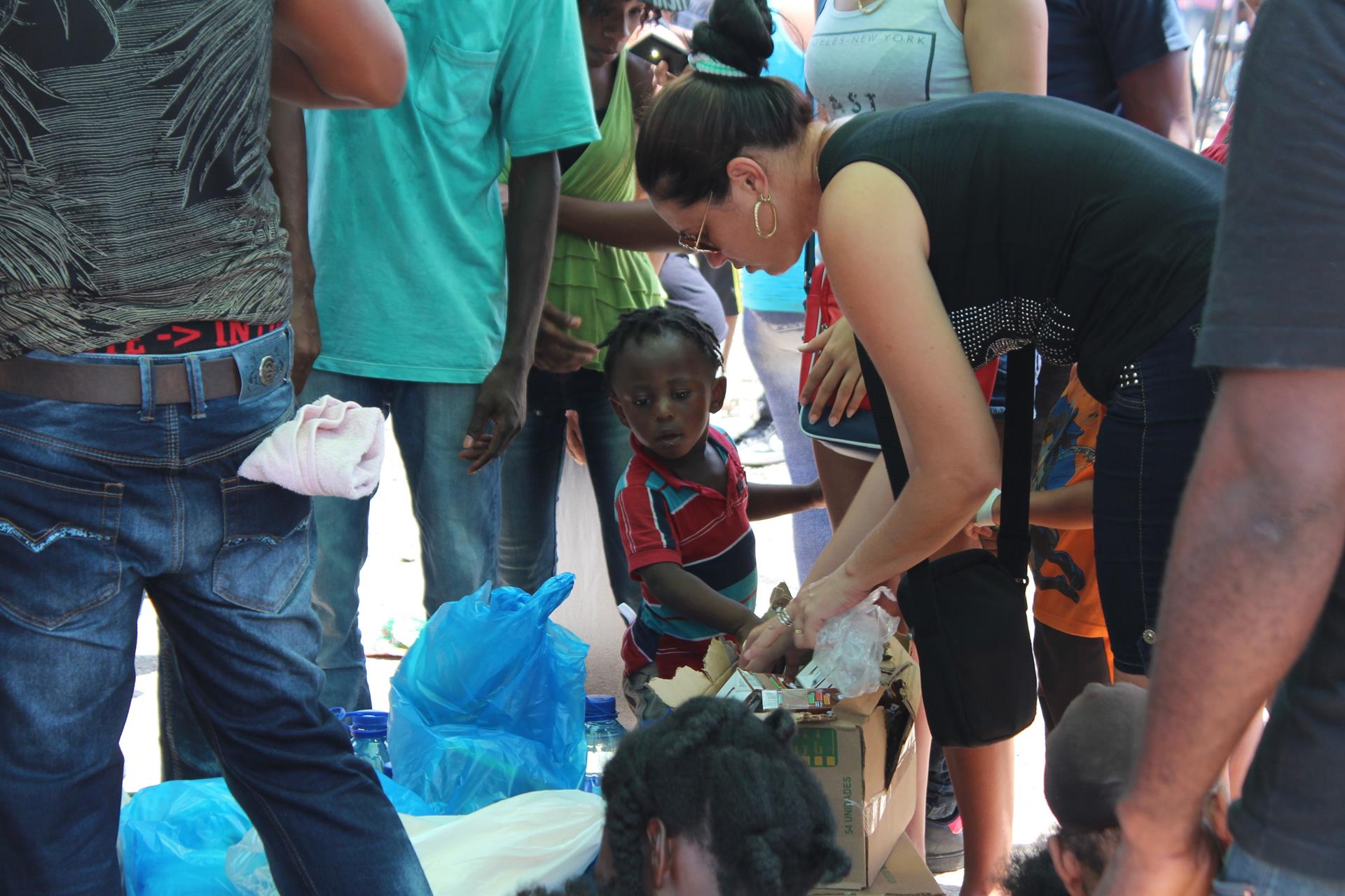 Una mujer entrega bebidas y alimentos a varios migrantes en Paso Canoas (Panamá).Imagen de archivo. EFE / Marcelino Rosario
