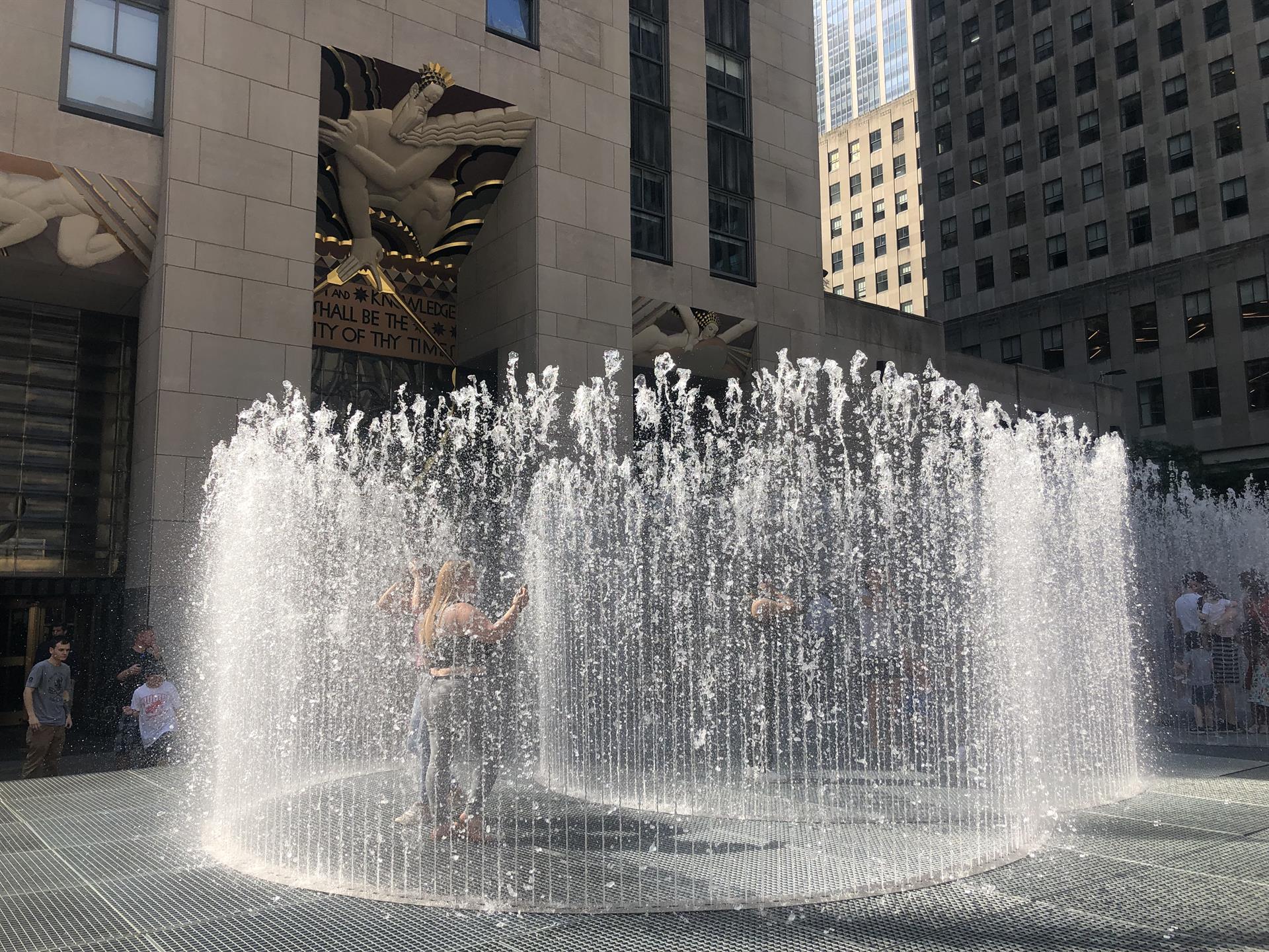 Unas personas se refrescan de la ola de calor dentro de las fuentes de agua pública en la plaza del Rockefeller Center en Nueva York (EE.UU.). EFE/BJavier Otazu
