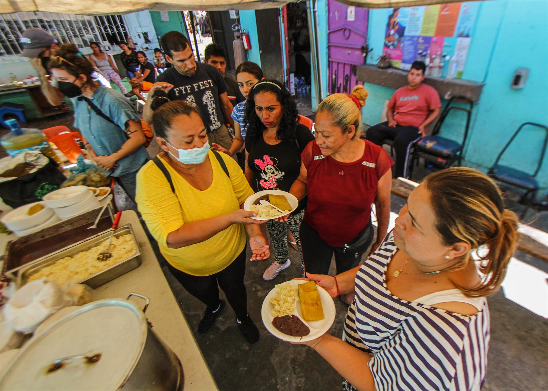 Migrantes reciben comida en el albergue 