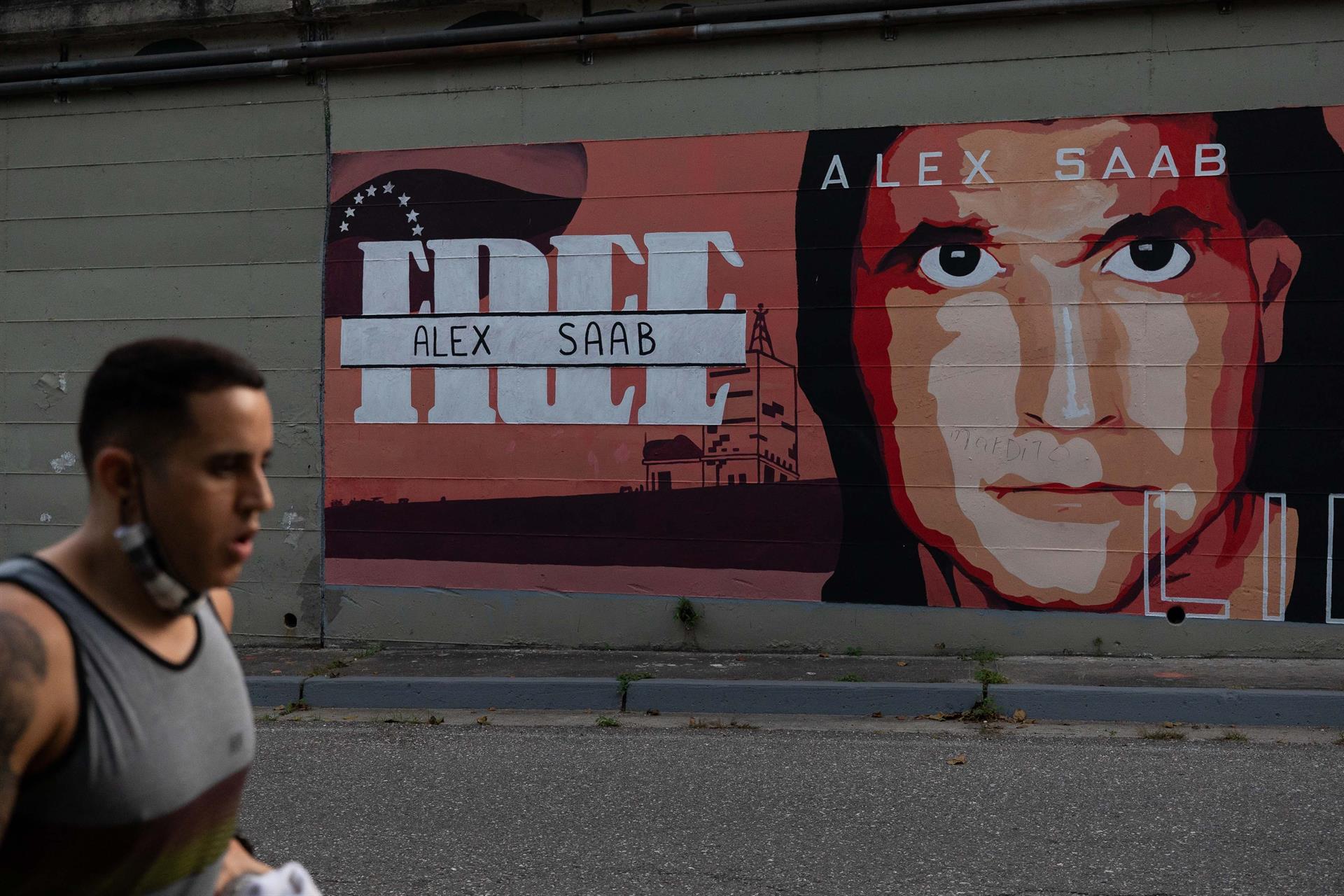 Un hombre camina frente a un mural con la imagen de Álex Saab. Fotografía de archivo. EFE/ Rayner Peña R.
