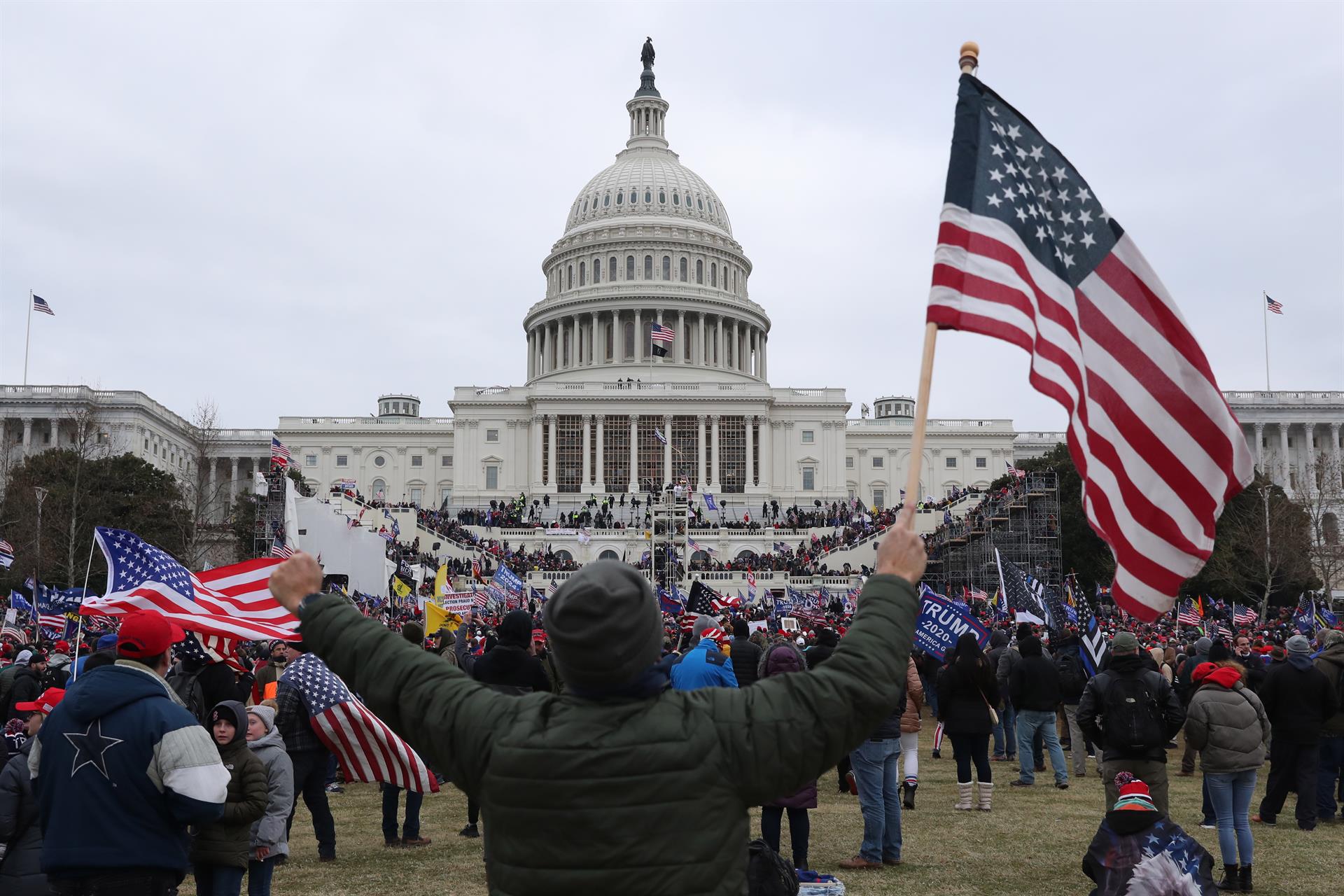 Imagen de archivo de un seguidor del expresidente Donald Trump sosteniendo la bandera de los Estados Unidos frente al Capitolio estadounidense, en Washington (Estados Unidos). EFE/ MICHAEL REYNOLDS
