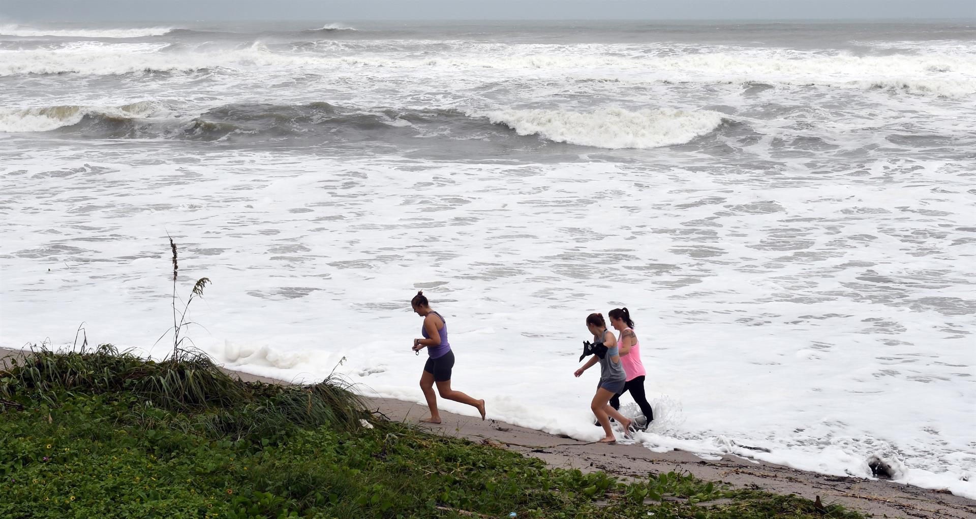 Curiosos caminan cerca de las olas que causa de un huracán en el paseo marítimo de Juno Beach, Florida (Estados Unidos). Imagen de archivo. EFE/ Jim Rassol
