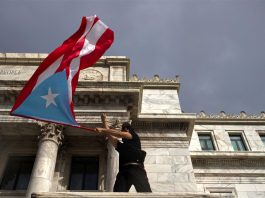 Fotografía de archivo que muestra a una persona ondeando una bandera puertorriqueña frente al Capitolio en San Juan, Puerto Rico. EFE/Thais LLorca

