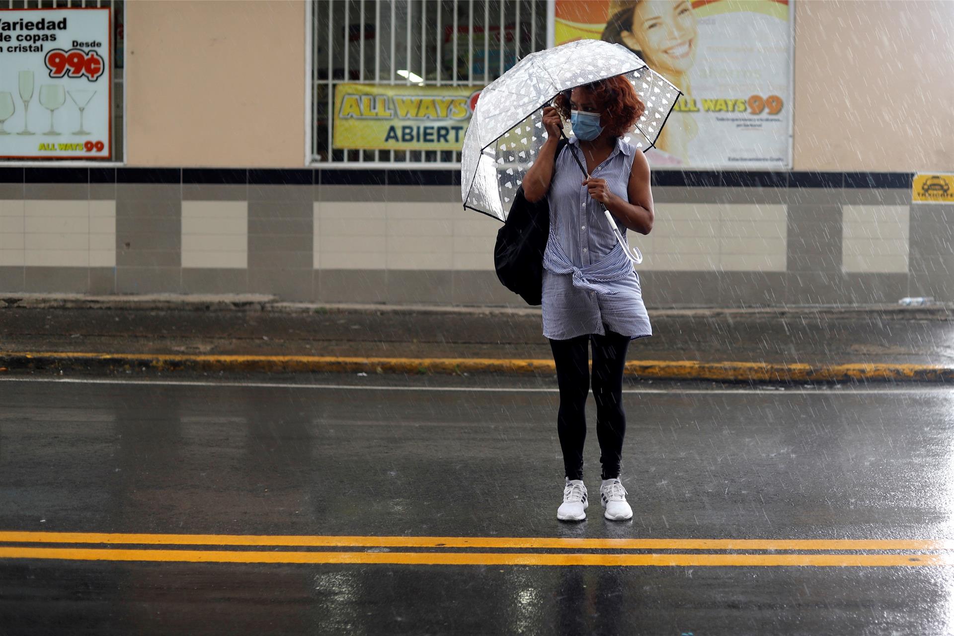 Fotografía de archivo de una mujer usando una sombrilla mientras cruza una calle en San Juan (Puerto Rico). EFE/Thais Llorca
