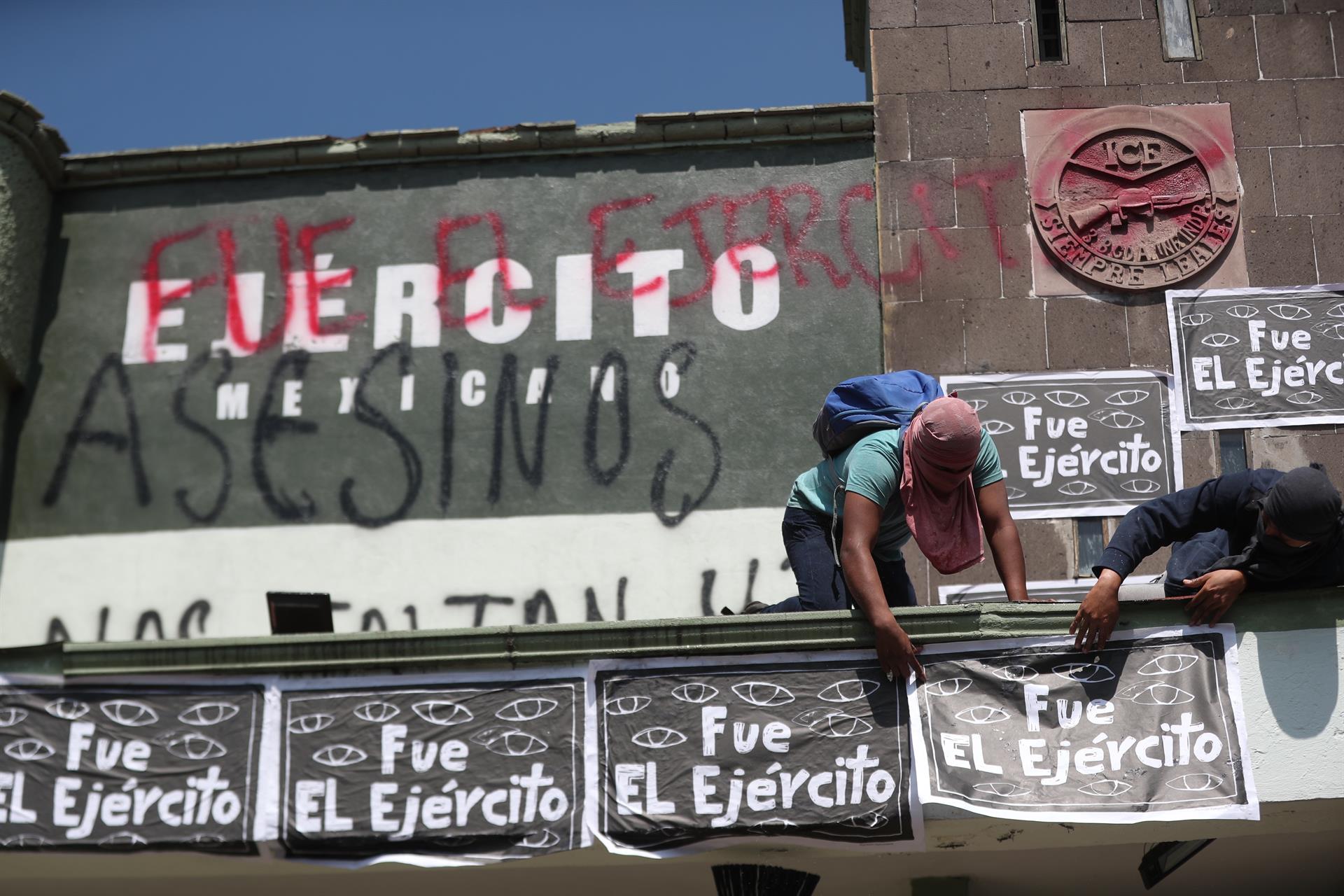 Dos hombres colocan carteles durante una manifestación por los 43 estudiantes desaparecidos de la Escuela Normal 