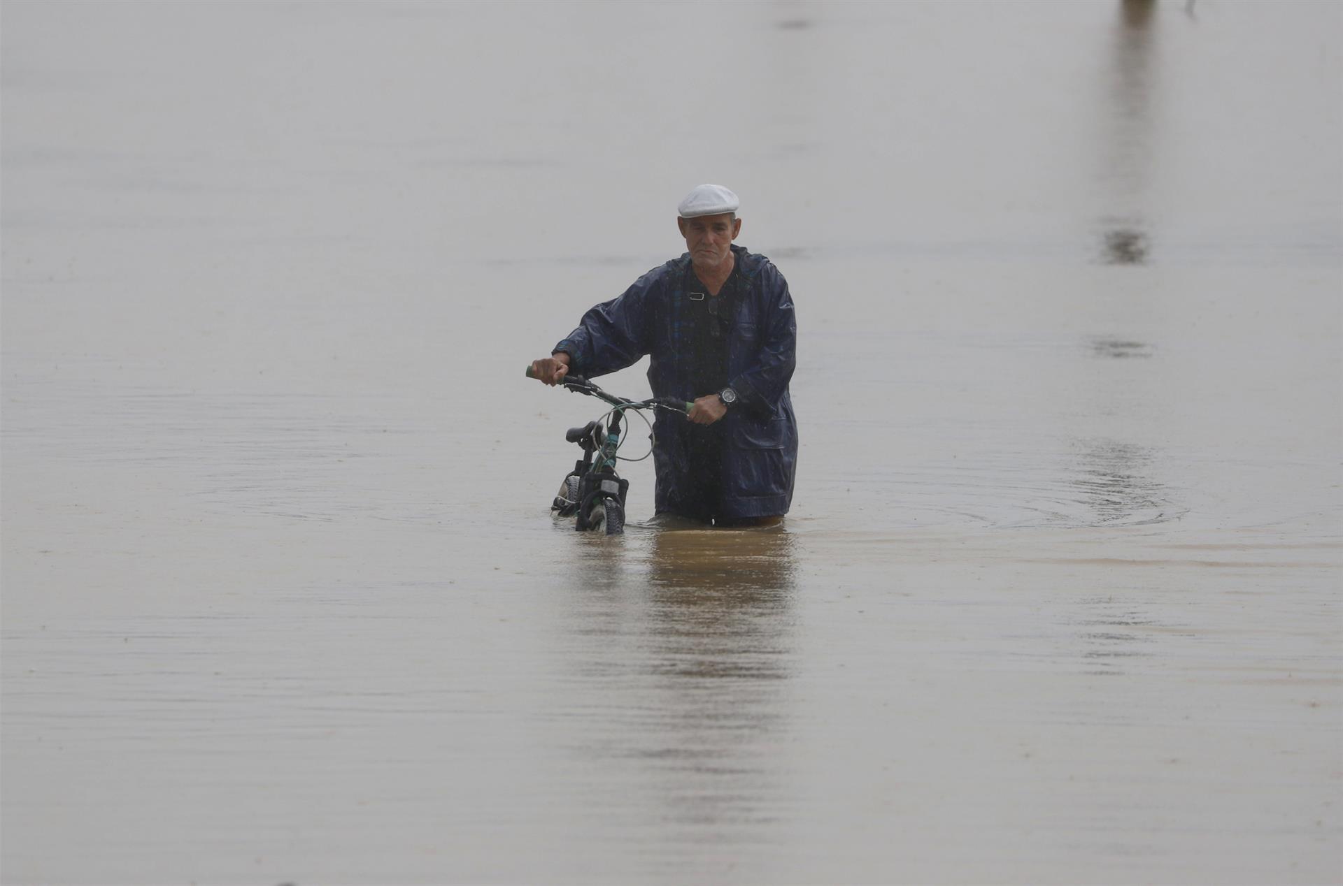 Un hombre cruza con su bicicleta una calle inundada debido a lluvias por el paso del huracán Fiona en Toa Baja (Puerto Rico). EFE/Thais LLorca
