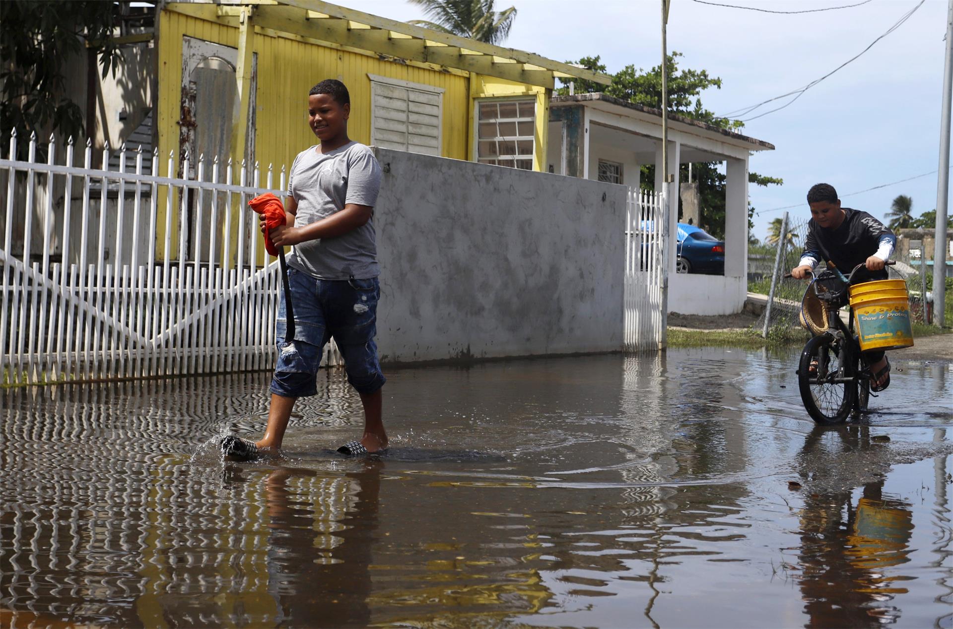 Jovani Correa (i) y Mariel Laureano intentan atrapar peces vivos que quedaron acumulados en una calle inundada tras el paso del huracán Fiona, hoy, en Loíza (Puerto Rico). EFE/ Thais Llorca
