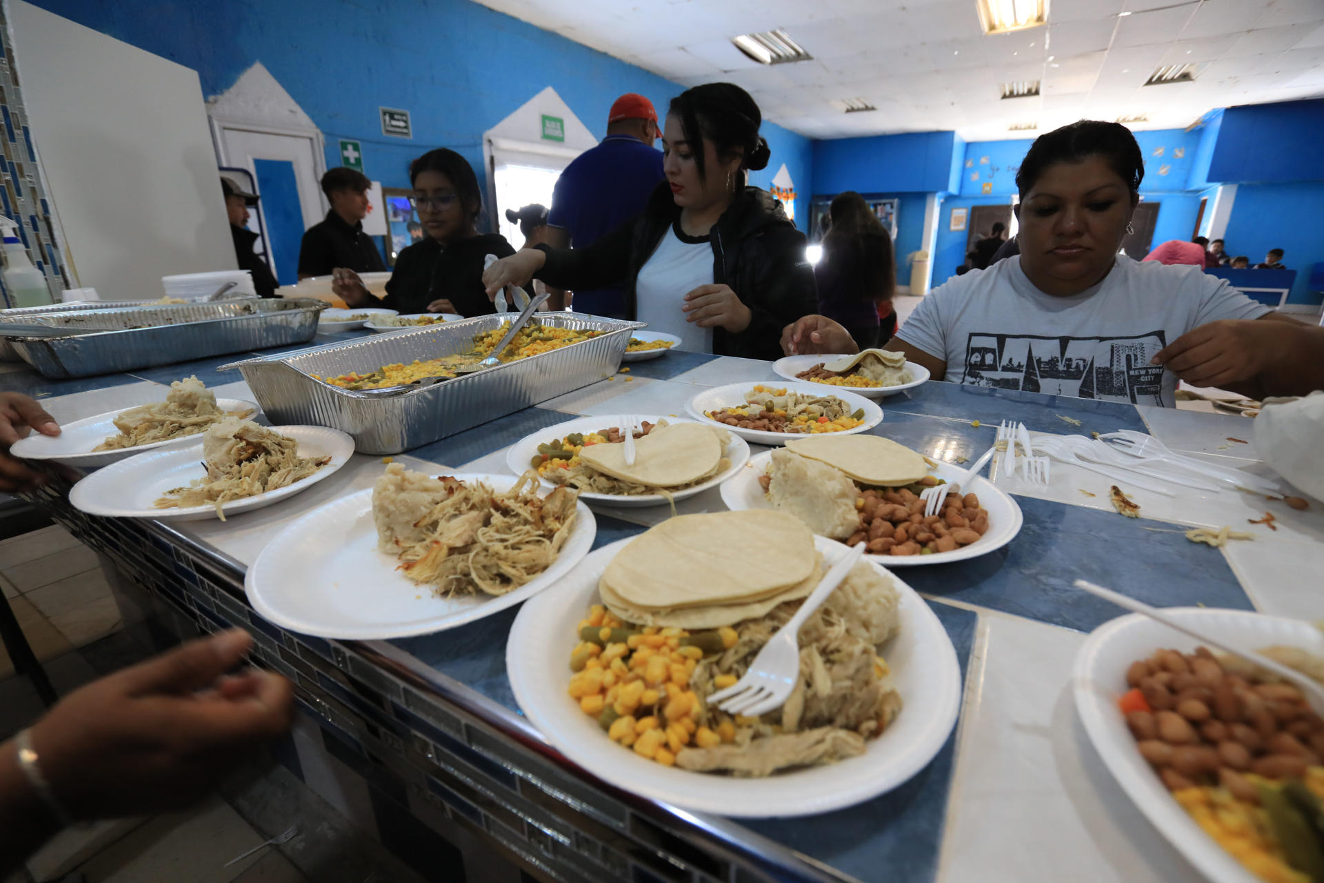 Migrantes reciben hoy alimentos en un campamento junto al Río Bravo con motivo del día de Acción de Gracias, en Ciudad Juárez, estado de Chihuahua (México). EFE/Luis Torres
