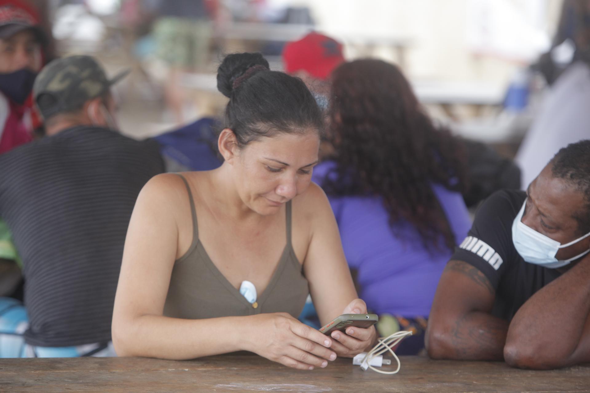 Una mujer es vista usando su celular en un campamento de migrantes procedentes de diversos países en Darién (Panamá). EFE/ Carlos Lemos
