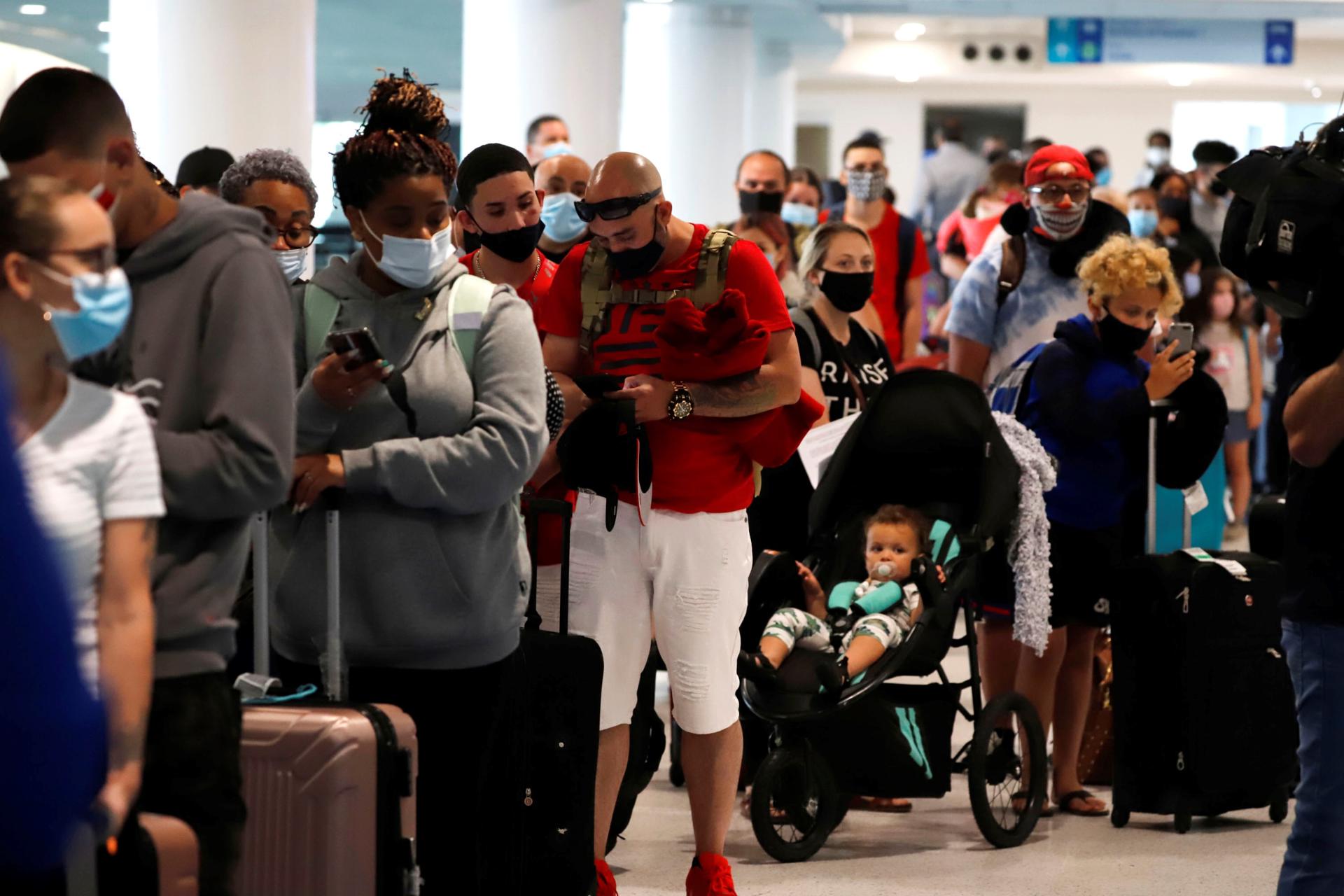 Unos pasajeros aguardan en cola para pasar las medidas de seguridad del COVID-19 en el Aeropuerto Luis Muñoz Marín en San Juan (Puerto Rico). Imagen de archivo. EFE/Thais Llorca
