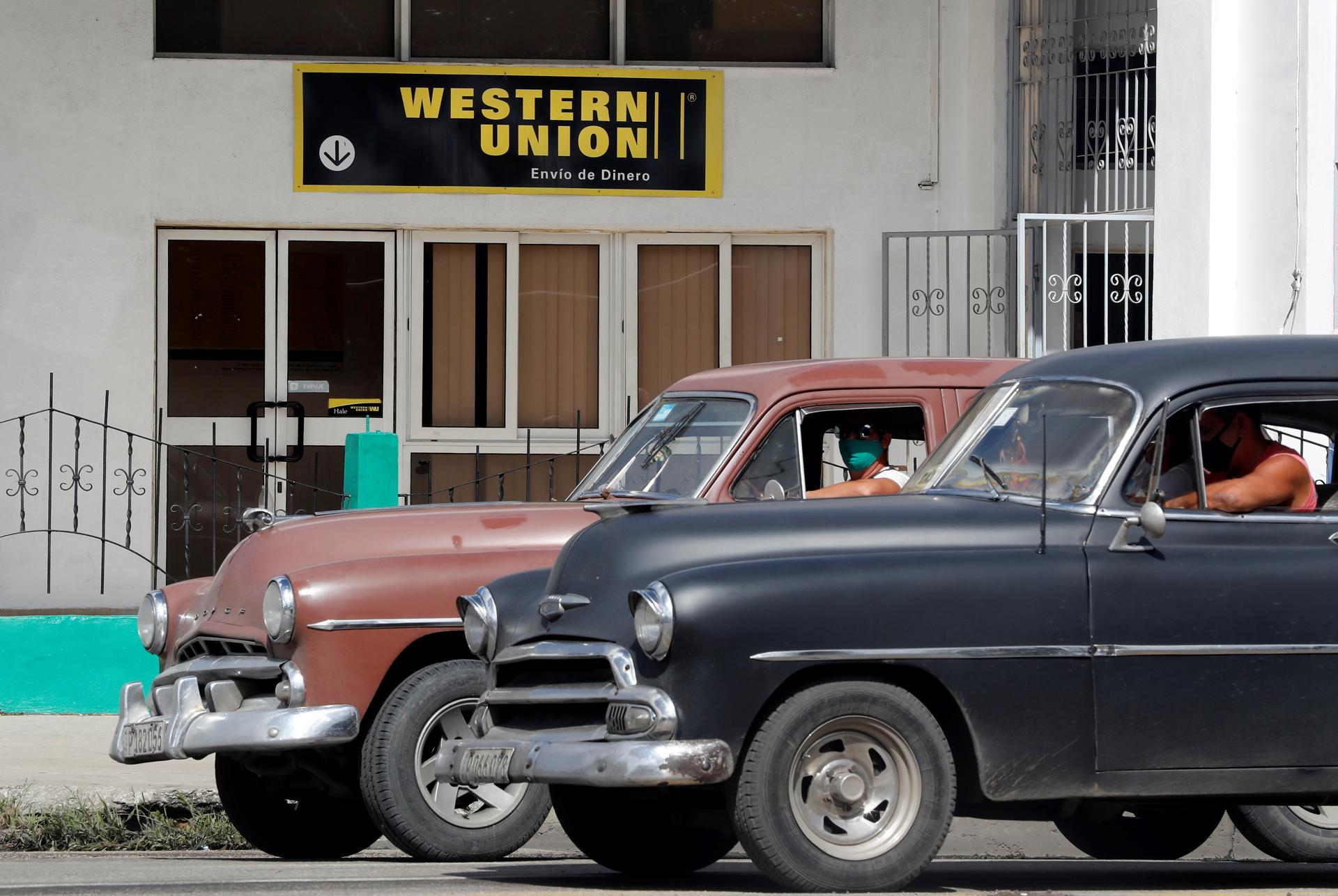 Dos autos clásicos pasan frente a una oficina de Western Unión en La Habana, Cuba. Imagen de archivo. EFE/Ernesto Mastrascusa
