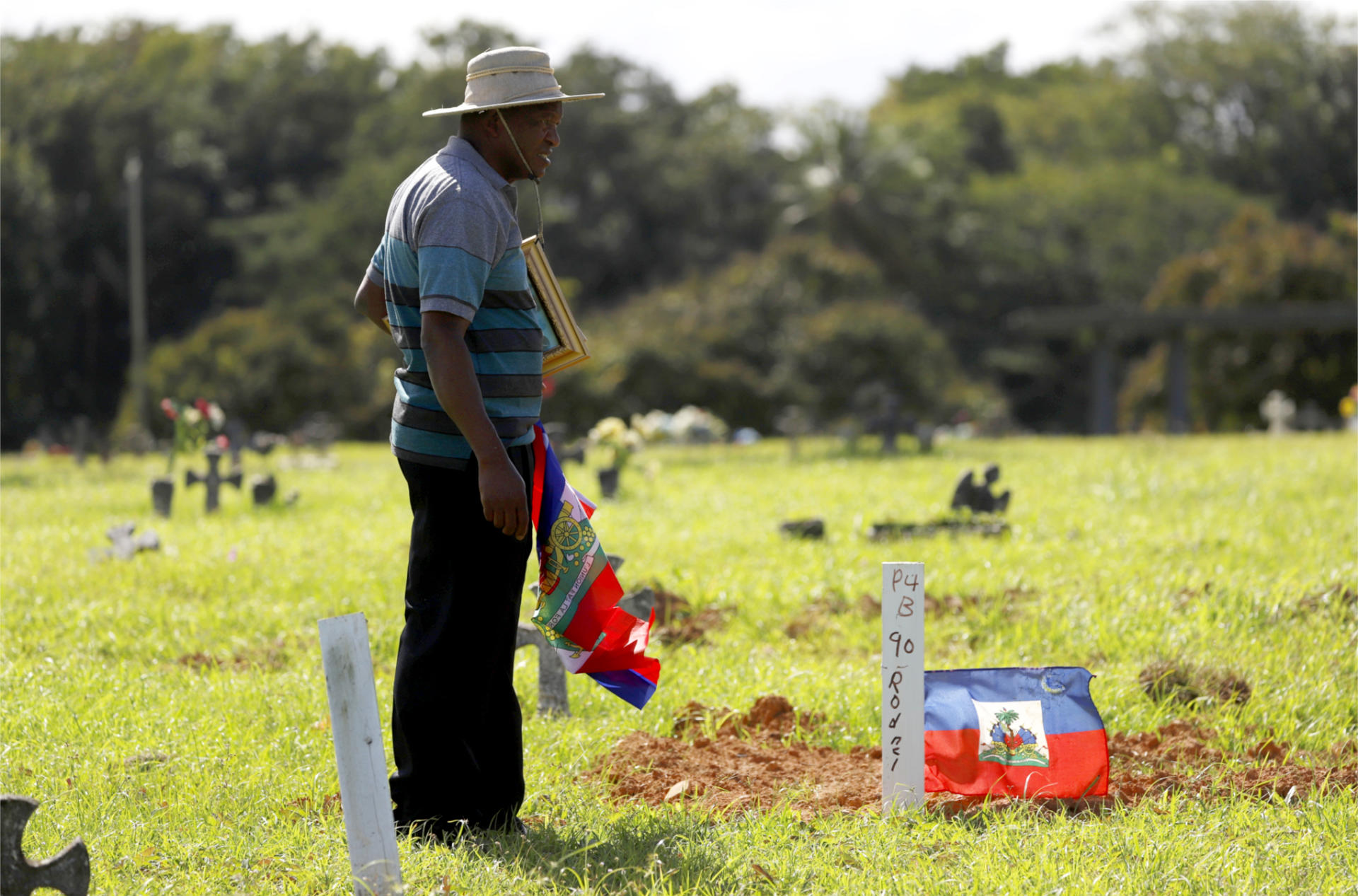 El líder comunitario de los haitianos en Puerto Rico, Leonard Prophil, coloca una bandera nacional durante una vista el lunes 23 de enero al cementerio de San Juan, Puerto Rico. EFE/Thais Llorca
