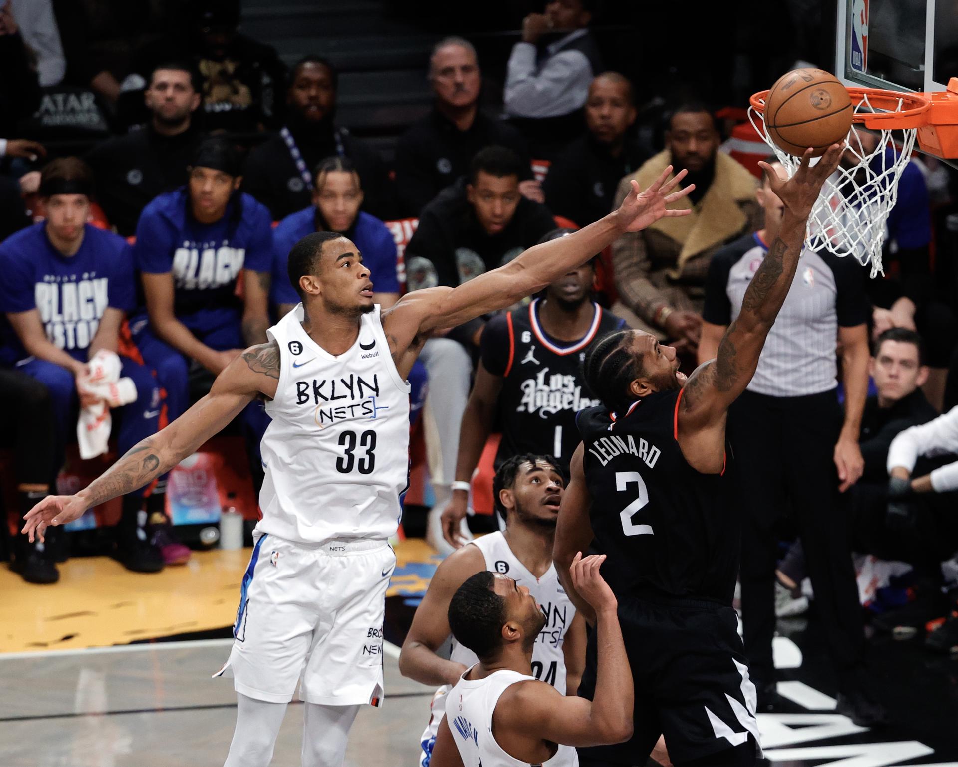 El alero de LA Clippers, Kawhi Leonard (D), lanza un tiro que pasa al centro defensor de los Nets de Brooklyn, Nic Claxton (I), y sus compañeros en la segunda mitad del partido de la NBA entre Los Angeles Clippers y los Brooklyn Nets en el Barclays Center de Brooklyn, Nueva York, EE.UU. EFE/EPA/JASON SZENES
