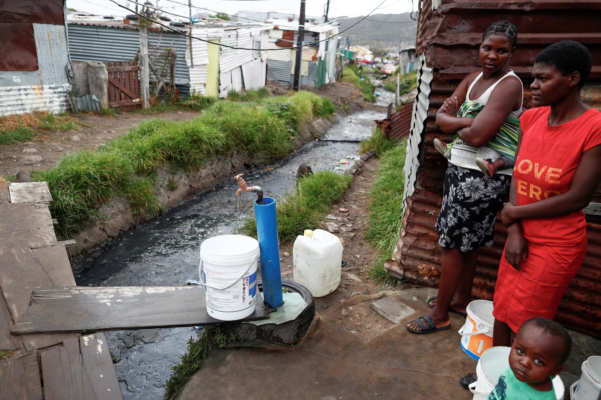 Fotografía de archivo en la que se registró a un par de mujeres al recolectar agua potable, en un grifo comunitario, en Ciudad del Cabo (Sudáfrica). EFE/Nic Bothma
