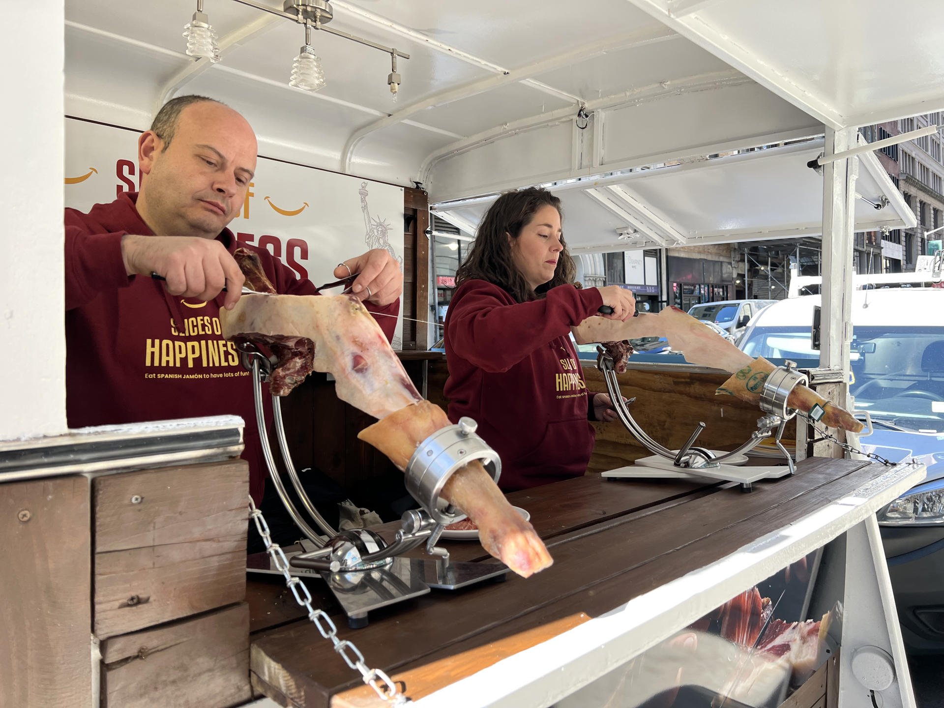 Las dos patronales del jamón español se unen para “vender felicidad” en EEUU Dos personas cortan hoy jamón ibérico en el "camión de la felicidad", en una calle de Nueva York (EE.UU). EFE/Sarah Yáñez-Richards