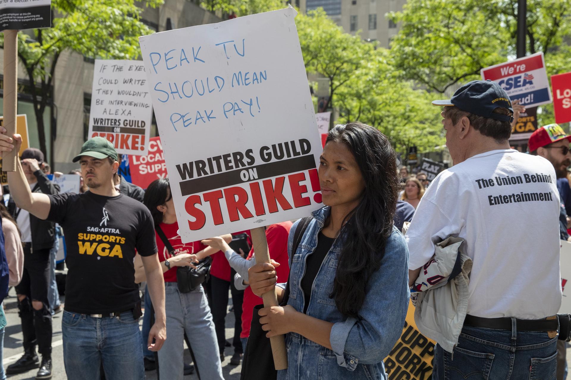 Fotografía de archivo del 23 de mayo donde aparecen unos manifestantes mientras sostienen pancartas de apoyo al Sindicato de Guionistas de Hollywood (WGA) durante el 