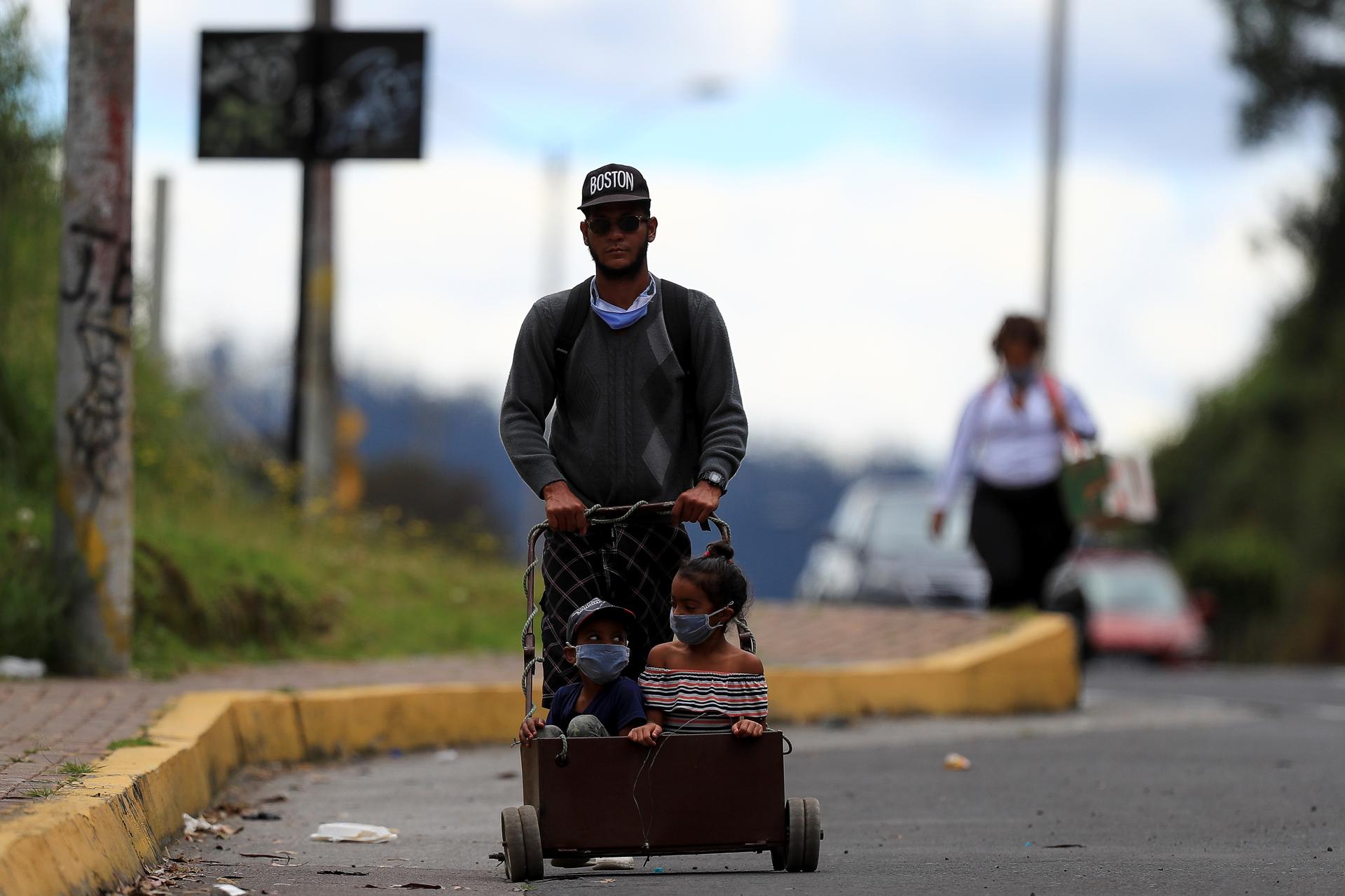 Fotografía de archivo de un migrante y dos niños caminando por la carretera. EFE/ José Jácome
