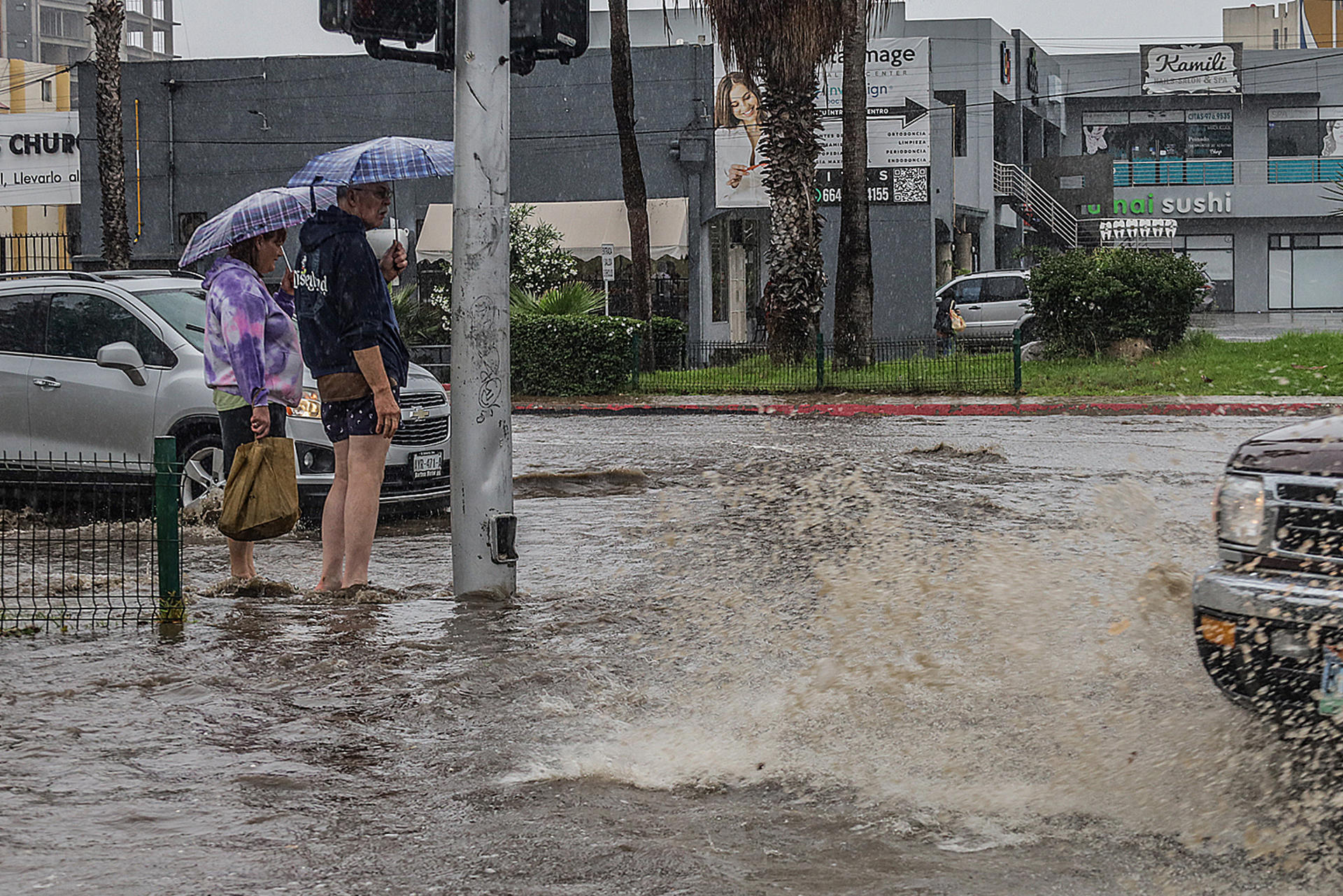 Una pareja sale de compras por una calle inundada en la ciudad de Tijuana (México). EFE/Joebeth Terriquez
