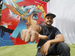 El artista colombiano Chota 13 posa junto a un mural suyo en el Espacio Iberia en Bogotá (Colombia). EFE/ Carlos Ortega
