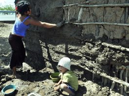 Fotografía de archivo de un niño y una joven que ayudan a construir una pared de lodo. EFE/Gustavo Amador
