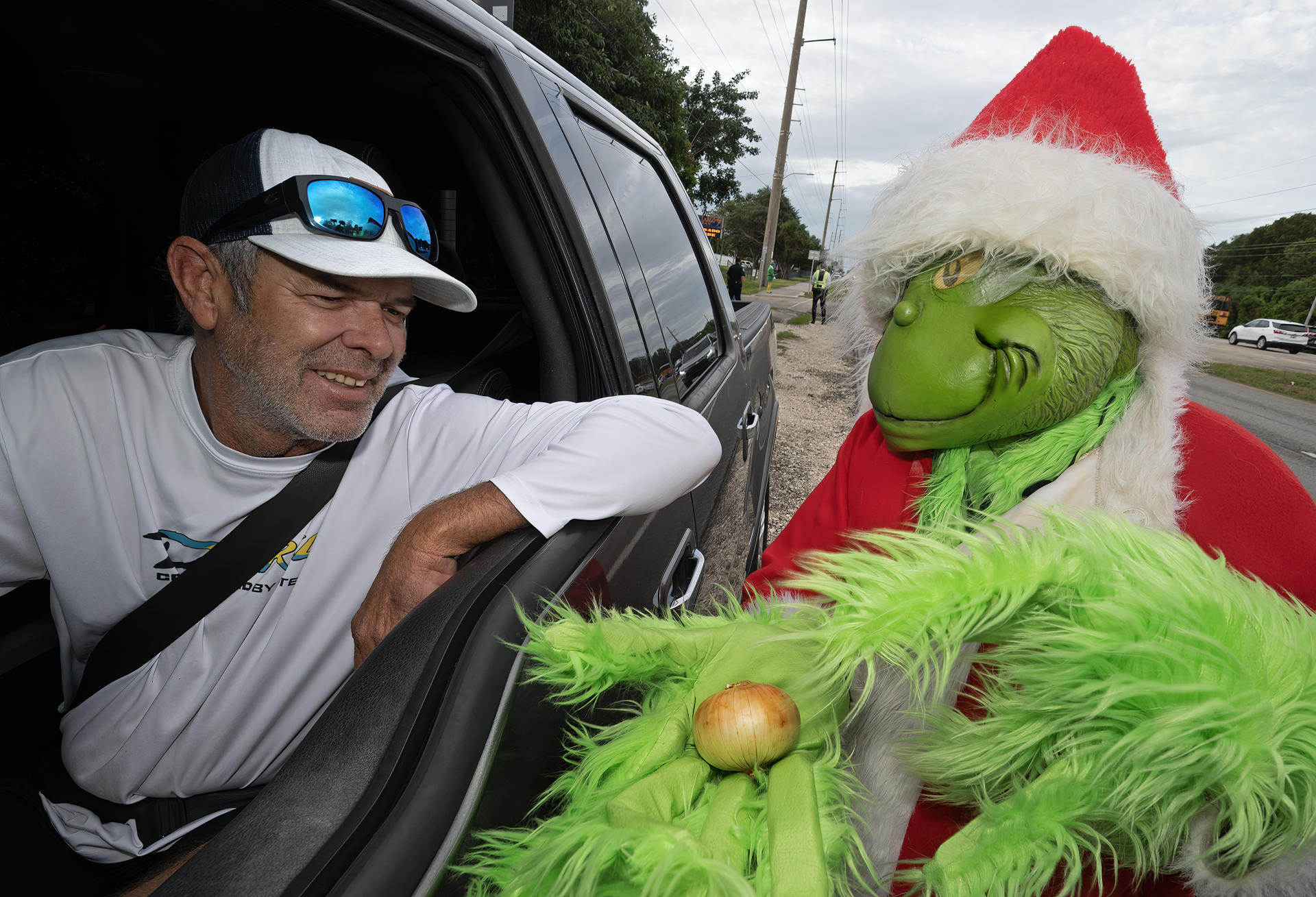 Alguacil disfrazado de duende ‘Grinch’ ofrece cebollas en vez de multas de tráfico Fotografía cedida por la Oficina de noticias de los Cayos de Florida donde aparece el coronel de la Oficina del Alguacil del Condado de Monroe, Lou Caputo (d), mientras ofrece una cebolla a un conductor en la autopista cercana a la escuela primaria Key Largo hoy viernes en Cayo Largo, Florida. EFE/Andy Newman/Florida Keys News Bureau /SOLO USO EDITORIAL /NO VENTAS /SOLO DISPONIBLE PARA ILUSTRAR LA NOTICIA QUE ACOMPAÑA /CRÉDITO OBLIGATORIO