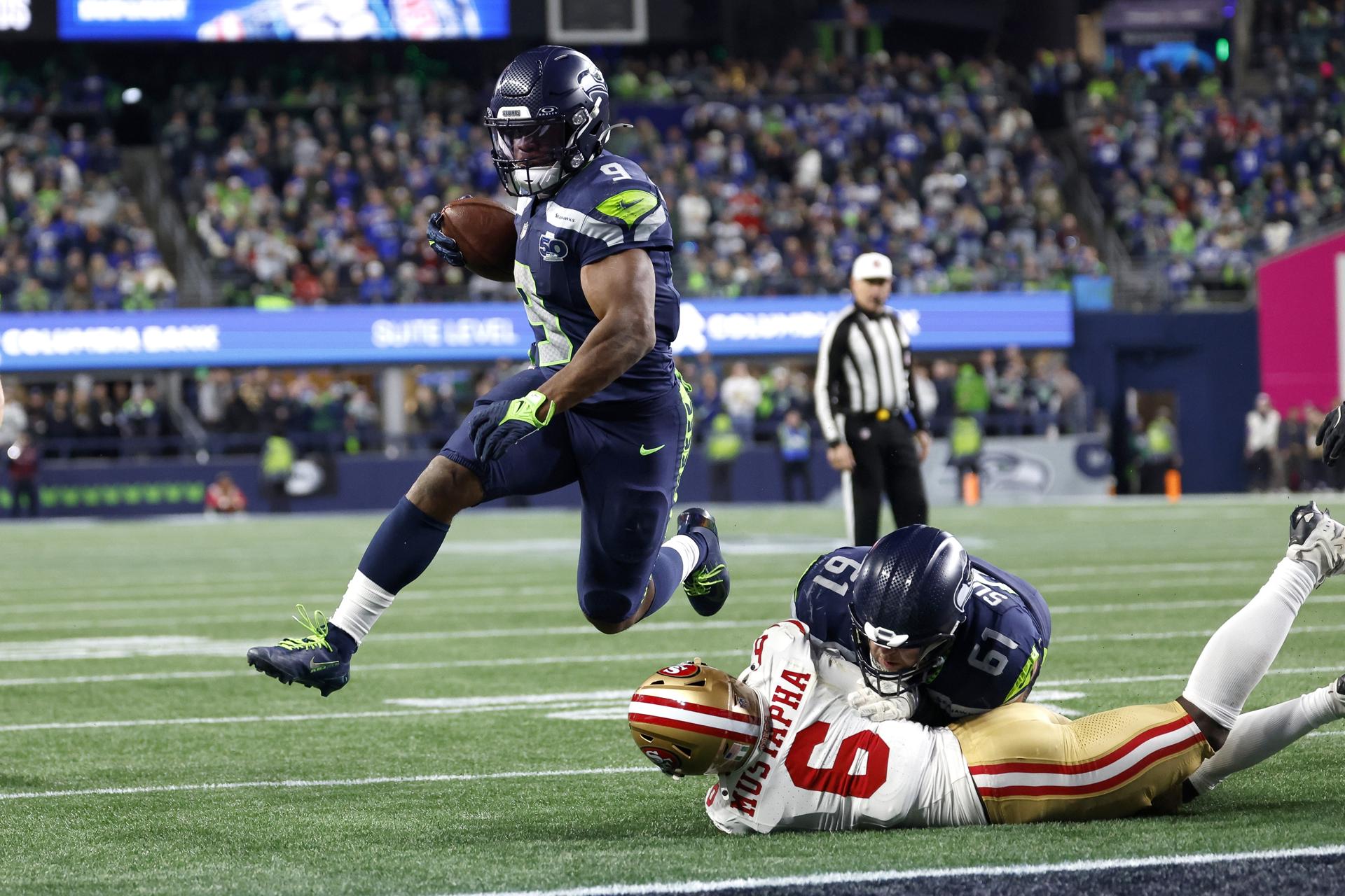 El corredor de los Seattle Seahawks, Kenneth Walker III (i), elude con un salto a Malik Mustapha de los San Francisco 49ers y anota un 'touchdown' este sábado durante el juego en Seattle (Washington). EFE/EPA/JOHN G. MABANGLO 