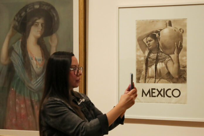 Una persona toma una fotografía durante un recorrido de la exposición 'México: ruta y destino' compuesta de cartografías, pinturas, carteles y fotografías que retratan el 