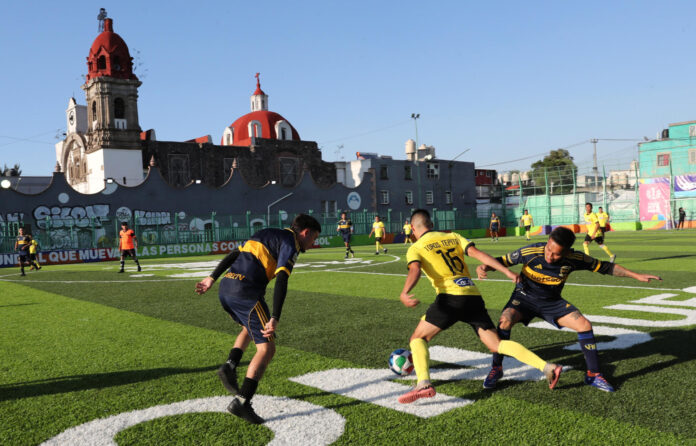 Personas juegan fútbol en una cancha ubicada en el barrio bravo de Tepito este lunes, en Ciudad de México (México). EFE/Mario Guzmán
