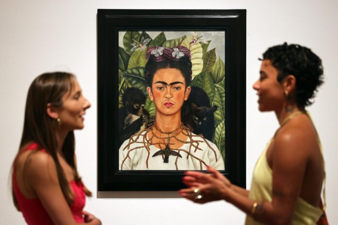 Personal del museo Tate Modern de Londres junto a un retrato de Frida Kahlo en la exposición 'Frida: La creación de un icono'. EFE/EPA/ANDY RAIN
