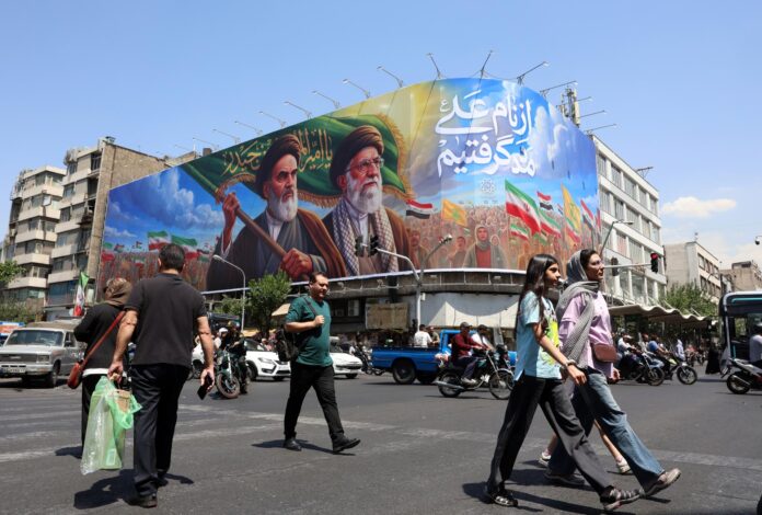 Ciudadanos iraníes pasan junto a una gran valla publicitaria con la imagen del difunto líder supremo iraní, el ayatolá Ruhollah Khomeini, y del líder supremo, el ayatolá Ali Khamenei, en una calle de Teherán, Irán, este miércoles. EFE/EPA/ABEDIN TAHERKENAREH RESTRICCIONES: Prohibido el acceso a medios de comunicación israelíes/canales de televisión en persa fuera de Irán/Estrictamente prohibido el acceso a BBC Persian/VOA Persian/Manoto TV/Televisión Internacional de Irán. (Según lo dispuesto por la Dirección General de Medios de Comunicación Extranjeros de Irán)
