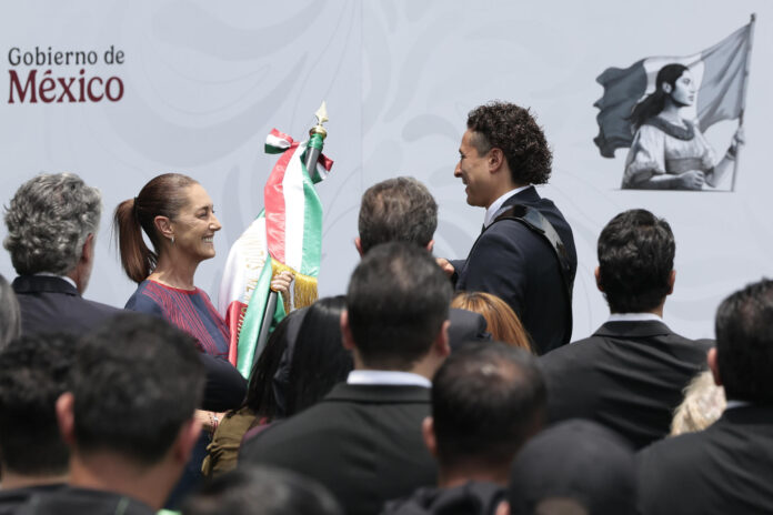 La presidenta de México, Claudia Sheinbaum (i), entrega una bandera al arquero Guillermo Ochoa durante la ceremonia de abanderamiento de la selección mexicana de fútbol este lunes, en el Centro de Alto Rendimiento de la Federación Mexicana de Fútbol en Ciudad de México (México). EFE/ José Méndez
