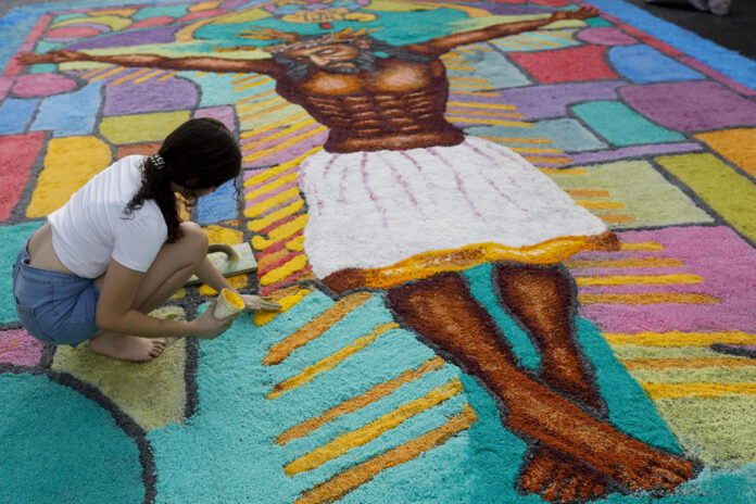 Una mujer fue captada este 4 de junio al realizar una alfombra de serrín con motivo de la Fiesta del Corpus Christi, en la Villa de Los Santos (Panamá). EFE/Bienvenido Velasco
