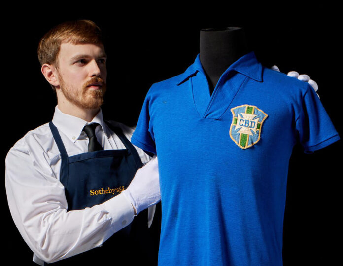 Fotografía tomada de la cuenta en X @Sothebys de la casa de subastas Sotheby's que muestra a una persona exhibiendo la camiseta que el futbolista brasileño Pelé llevó en la final del Mundial de 1958 y que se estima será subastada en 6 millones de dólares en julio en Nueva York (EE.UU.). EFE/ @Sothebys /SOLO USO EDITORIAL/NO VENTAS/ SOLO DISPONIBLE PARA ILUSTRAR LA NOTICIA QUE ACOMPAÑA (CRÉDITO OBLIGATORIO)
