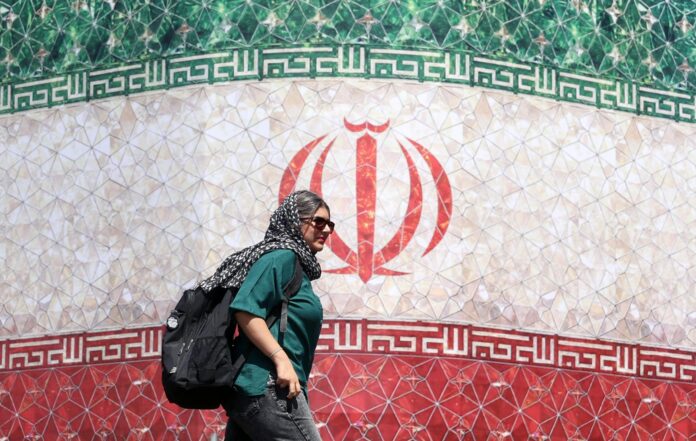 Una mujer iraní pasa junto a una valla publicitaria con la bandera nacional de Irán en la plaza Enqelab de Teherán, Irán. EFE/EPA/ABEDIN TAHERKENAREH. RESTRICCIONES: Prohibido el acceso a medios de comunicación israelíes/canales de televisión en persa fuera de Irán/Prohibido el acceso a BBC Persian/VOA Persian/Manoto TV/Televisión Internacional de Irán. (Según lo dispuesto por la Dirección General de Medios de Comunicación Extranjeros de Irán).
