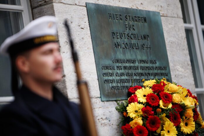 Una placa junto a una corona de flores dice  «Aquí murieron por Alemania el 20 de julio de 1944...» durante un acto en memoria de quienes fueron asesinados por su resistencia a la tiranía nazi en el Bendlerblock de Berlín, Alemania, este lunes.  EFE/EPA/CLEMENS BILAN
