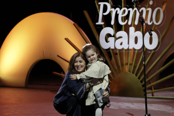 La periodista colombiana Catalina Gómez Ángel abraza a una niña luego de recibir el Reconocimiento a la Excelencia del Premio Gabo 2026 este viernes, en el Teatro Municipal Jorge Eliécer Gaitán, en Bogotá (Colombia). EFE/ Carlos Ortega
