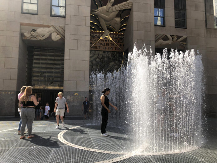Unas personas se refrescan de la ola de calor dentro de las fuentes de agua pública, en la plaza del Rockefeller Center en Nueva York (EE.UU.). EFE/Javier Otazu
